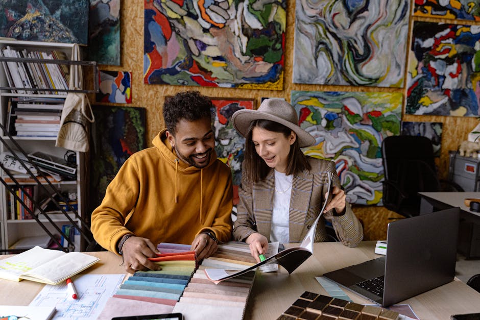 Two designers reviewing fabric samples and catalogs, surrounded by abstract art in a modern studio.